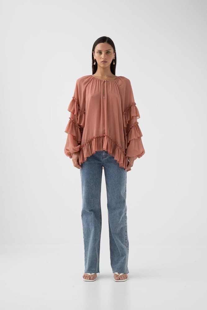 The uploaded product photo: the dusty-rose ruffled chiffon blouse worn straight-on against a plain white studio wall, evenly lit and unstyled.